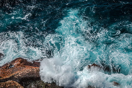 photo of body of water beside rock during daytime thumbnail