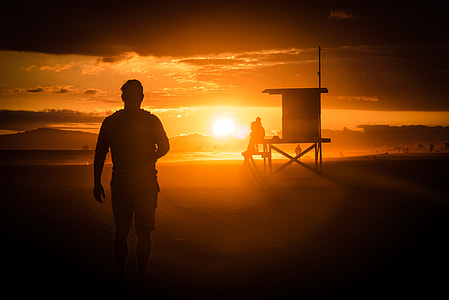 man's silhouette standing near brown house thumbnail