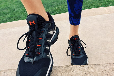 person wearing blue pants and pair of black Under Armour running shoes near grass field thumbnail