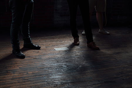 three people standing on brown wooden floor thumbnail