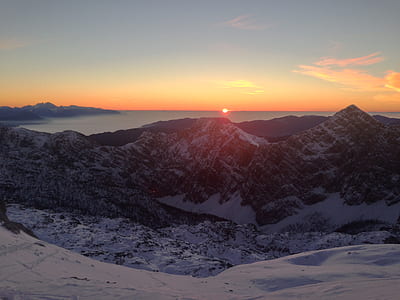 mountain covered with snow near body of water at golden hour thumbnail