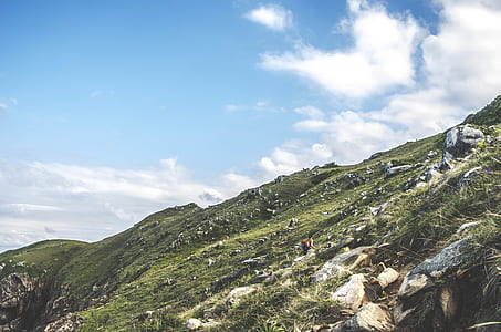 person climbing hill under cloudy sky thumbnail