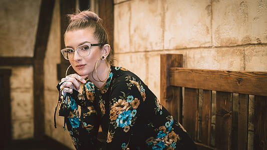 woman in black-brown-and-blue floral long-sleeved top sitting on outdoor bench thumbnail