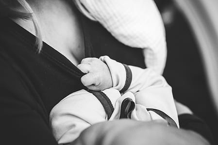 grayscale photography of baby holding mother's shirt thumbnail