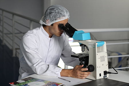 man in white long-sleeved shirt while using microscope thumbnail