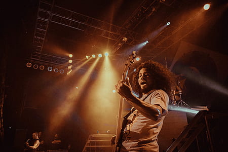 closeup photography of man playing guitar on stage with lights turned on thumbnail