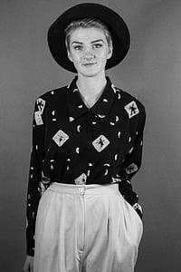 woman standing wearing black hat near gray wall thumbnail