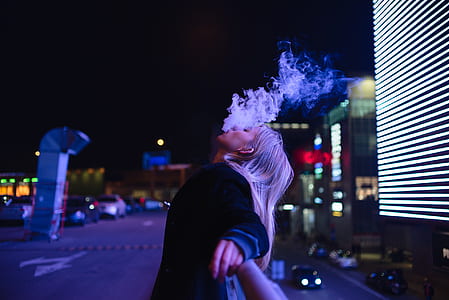 woman smoking on street road during night time thumbnail