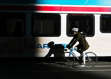 person riding bike near white and red train thumbnail