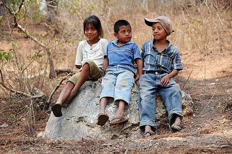 two boy and one girl sitting on rock during daytime thumbnail