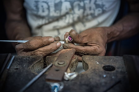 person fixing silver-colored and pink gemstone ring thumbnail