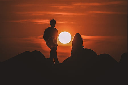 silhouette photo of man and woman on top of mountain during sunset thumbnail