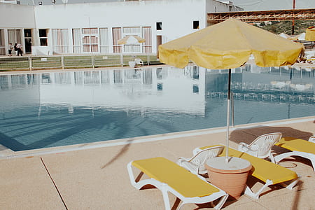 lounges and patio umbrella near swimming pool thumbnail