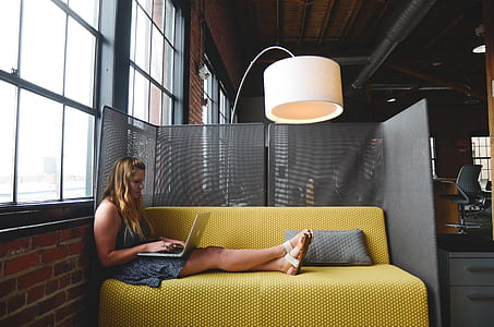 woman sitting on yellow couch holding laptop thumbnail