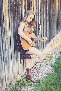 woman wearing brown sleeveless top playing guitar during daytime thumbnail