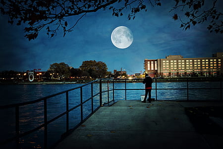 person standing near the railing while staring at the moon thumbnail