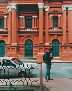 man standing beside silver car thumbnail