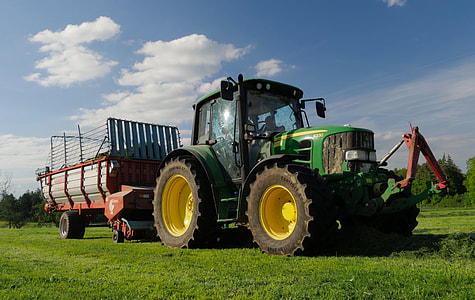 red tractor with trailer park on grass field at daytime thumbnail