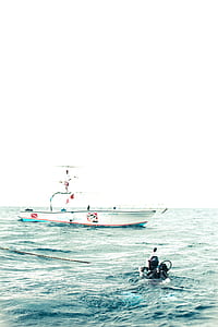 diver near white boat during daytime thumbnail