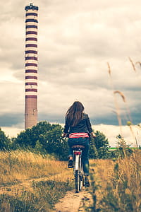 Woman Riding Bicycle Near Lighthouse thumbnail
