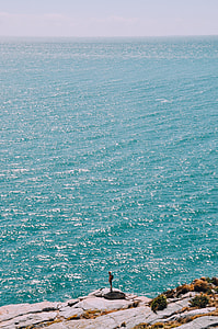 person standing on rock across body of water thumbnail