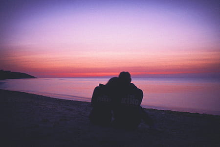 silhouette of couple sitting on seashore thumbnail