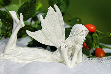 white ceramic fairy lying on white textile thumbnail