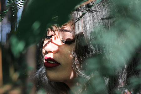 selective focus of woman hiding behind leaves thumbnail