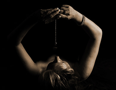 person wearing silver-colored bracelet holding silver-colored necklace thumbnail