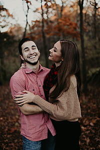 man in pink collared shirt embracing woman in brown sweater thumbnail