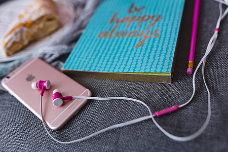 Blue notebook with a pink iPhone, headphones and a sweet bun thumbnail