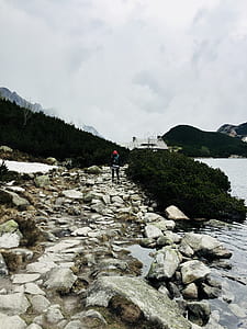 person standing on stone near body of water thumbnail