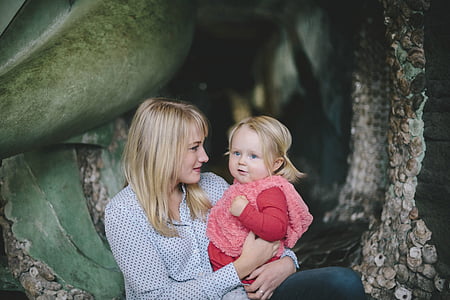 woman sitting while holding girl thumbnail