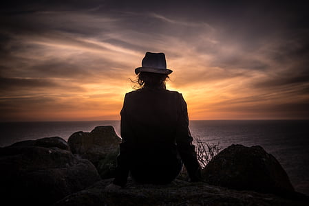 silhouette photograph of person sitting on mountain cliff thumbnail