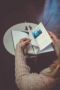 person opening book page on white desk thumbnail