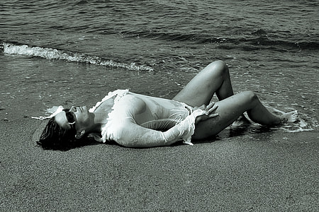 gray scale photo of laying woman on seashore thumbnail