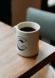 white ceramic mug full of coffee on brown table thumbnail