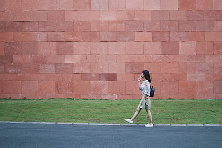 woman walking in front of brown concrete wall thumbnail