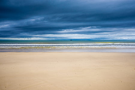 white sand shoreline under cloudy sky thumbnail