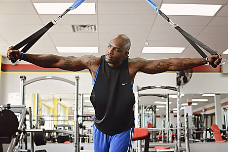 man in black tank top using resistant bands inside gym thumbnail