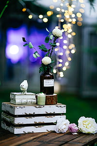 amber glass jar with white cluster flowers on top of white wooden pallet side table thumbnail