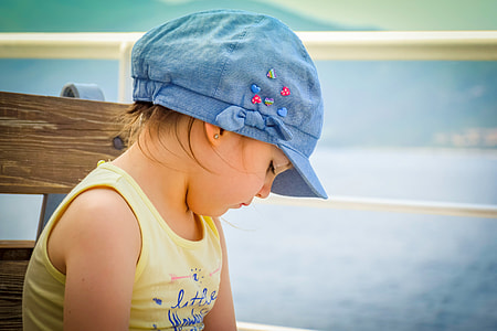 selective focus photography of girl sitting on chair while looking downward thumbnail