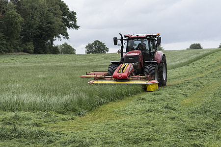 red tractor mowing grass field at daytime thumbnail