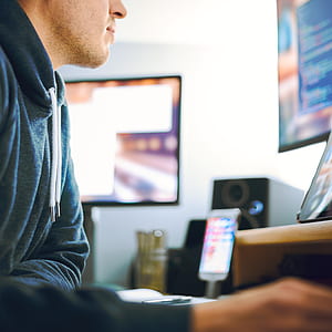 man in blue pullover hoodie in front of table and using computer thumbnail