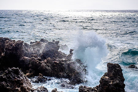 ocean waves on shore stones under white sky thumbnail