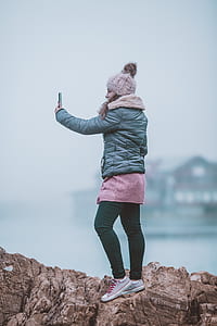 woman wearing bobble hat holding smartphone thumbnail