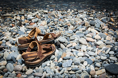 pair of brown sandals on gray stones thumbnail