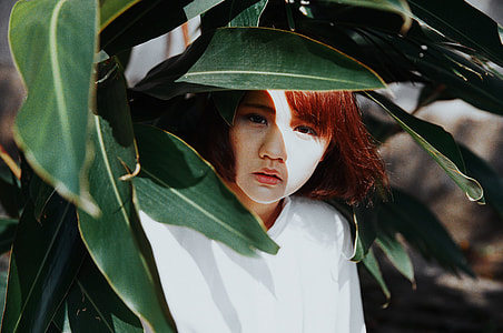 woman hiding from green plants during daytime thumbnail