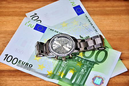 chronograph watch on 100 Euro banknote on brown wooden surface thumbnail