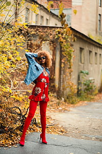 woman standing on gray pavement near yellow leaf plant near building at daytime thumbnail